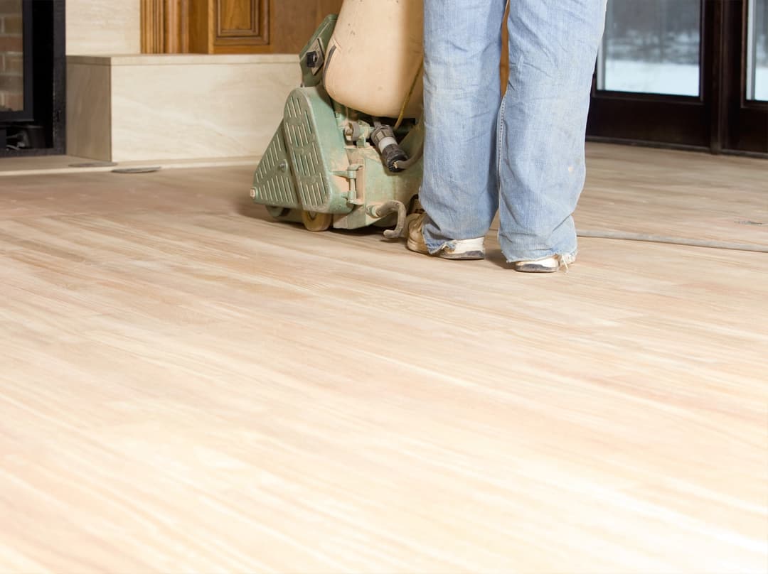Hardwood floor being sanded down to bare wood